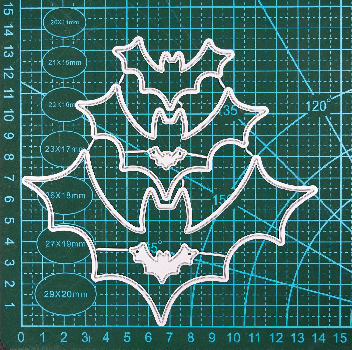 Set of bat shaped nesting metal cutting dies displayed on cutting mat for scale