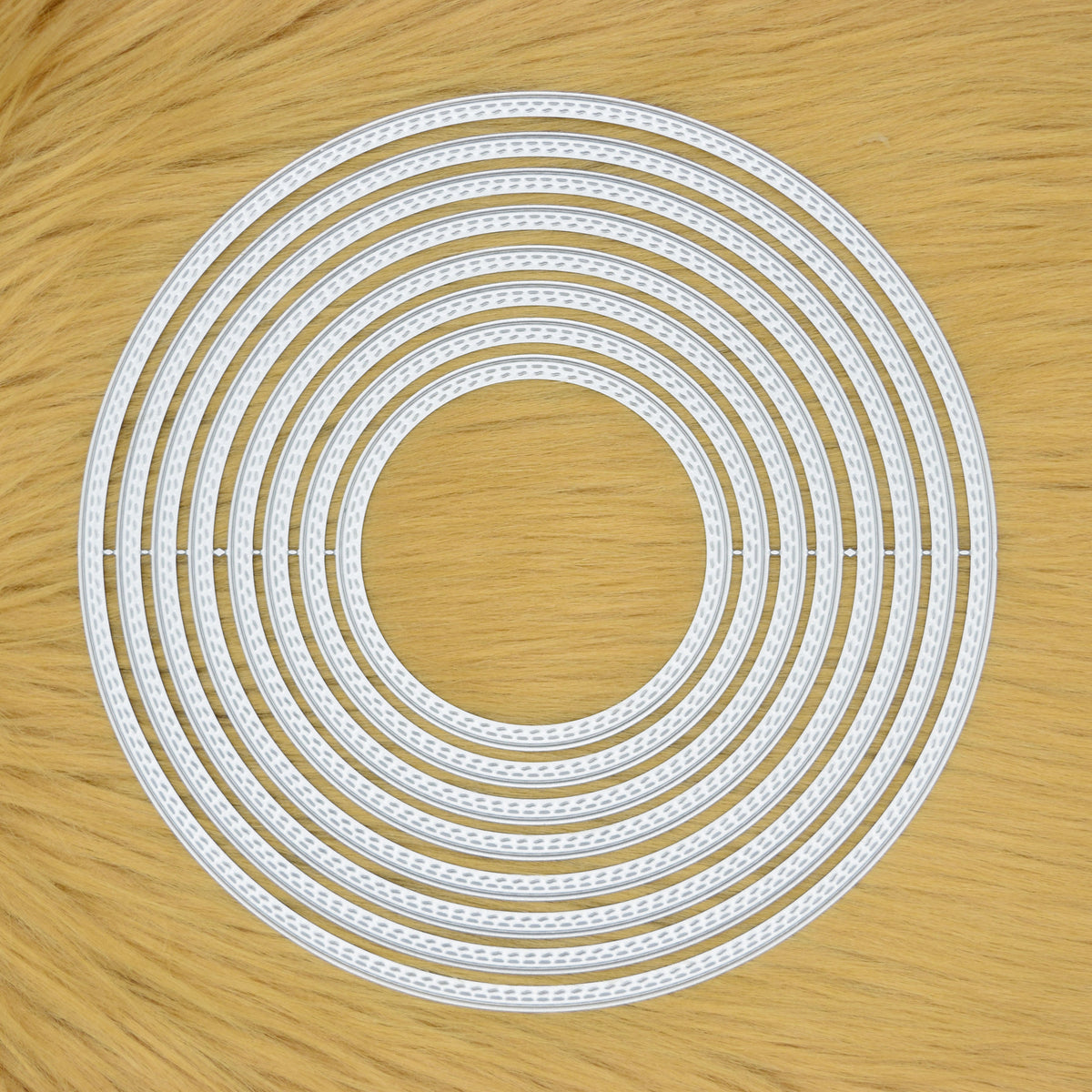 Set of eight large double stitch circle nesting metal cutting dies displayed on a tan faux fur background.
