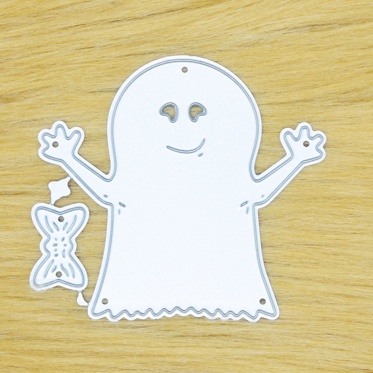 Ghost and bow metal cutting die set displayed on a tan faux fur background showing the full connected design.