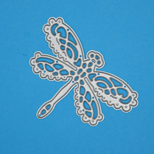 Decorative lace dragonfly metal cutting die on blue background for card making scrapbooking and paper craft projects
