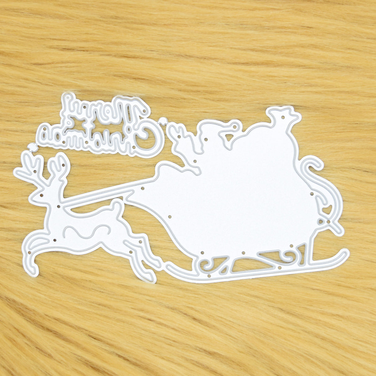 Santa sleigh and reindeer metal cutting die set with Merry Christmas sentiment on a tan faux fur background.