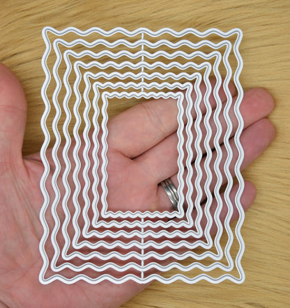 Wavy rectangle nesting dies shown in hand for size reference