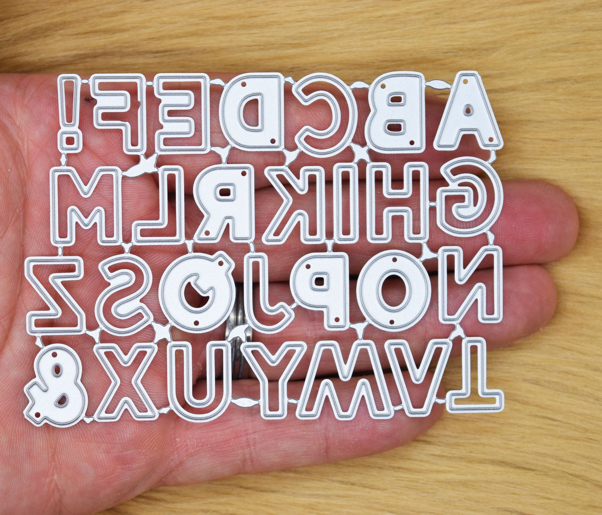 Alphabet metal cutting dies set shown in hand for card making and papercrafts