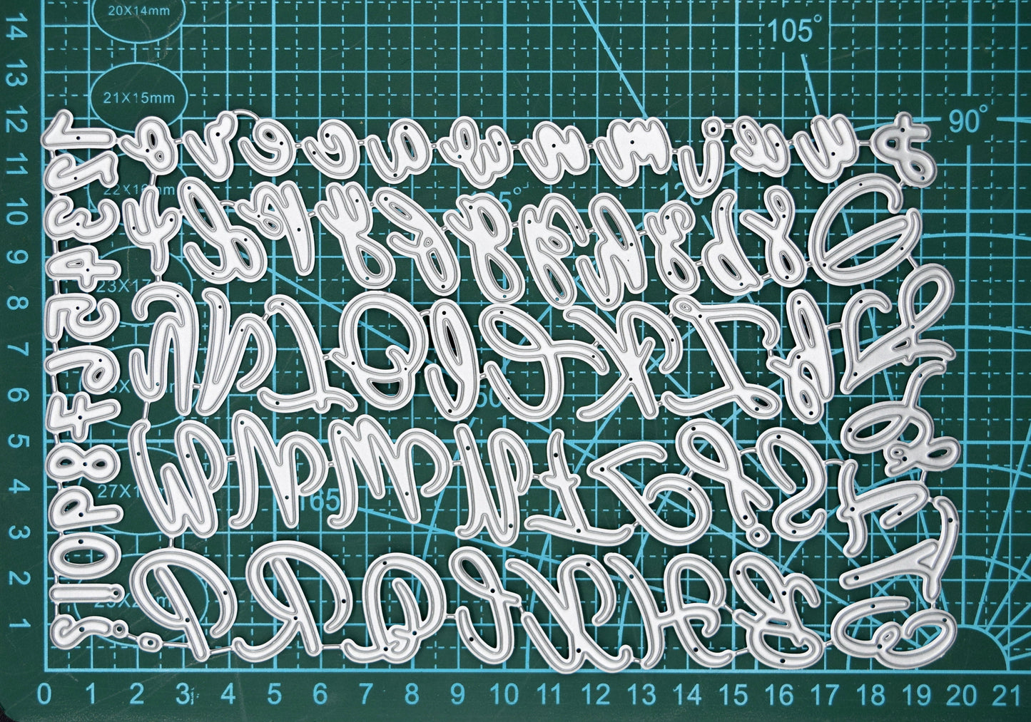 Uppercase & lowercase alphabet and numbers metal cutting dies set displayed on a cutting mat to show scale for card making and paper crafting.