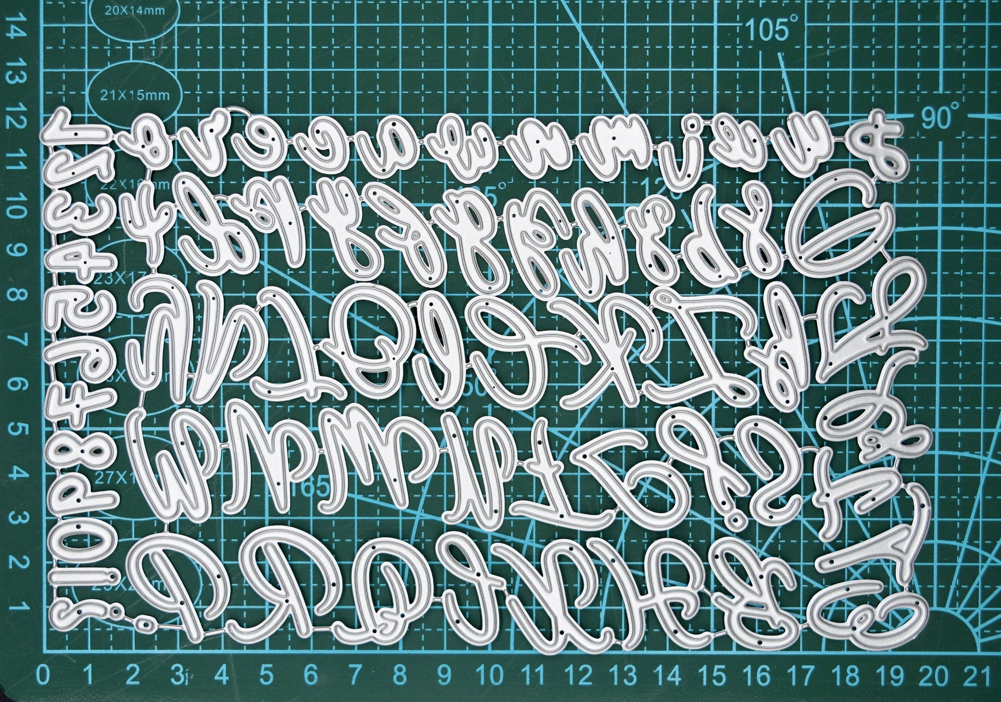 Uppercase & lowercase alphabet and numbers metal cutting dies set displayed on a cutting mat to show scale for card making and paper crafting.