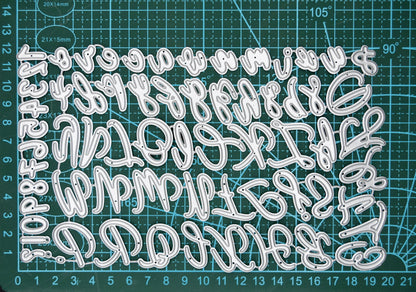 Uppercase & lowercase alphabet and numbers metal cutting dies set displayed on a cutting mat to show scale for card making and paper crafting.