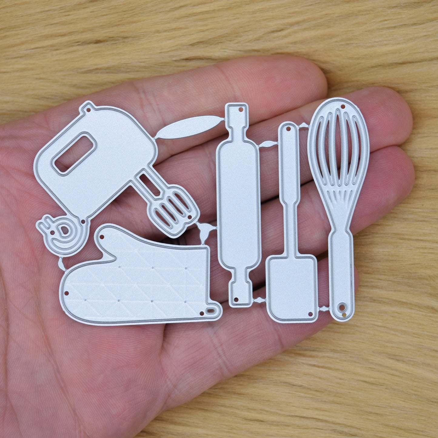 Baking utensil cutting dies held in hand for size reference