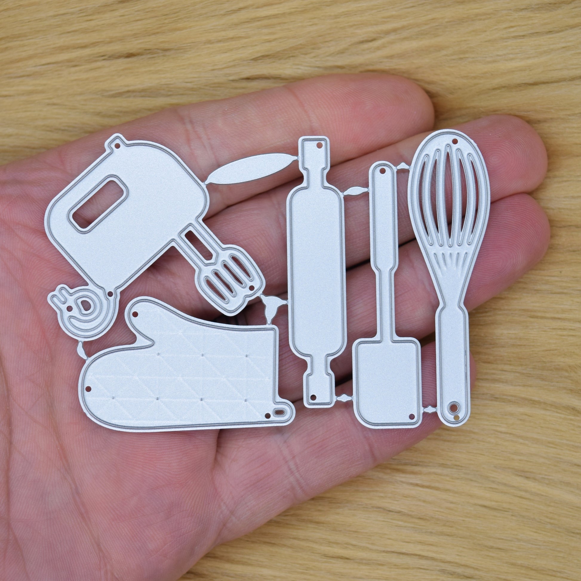 Baking utensil cutting dies held in hand for size reference