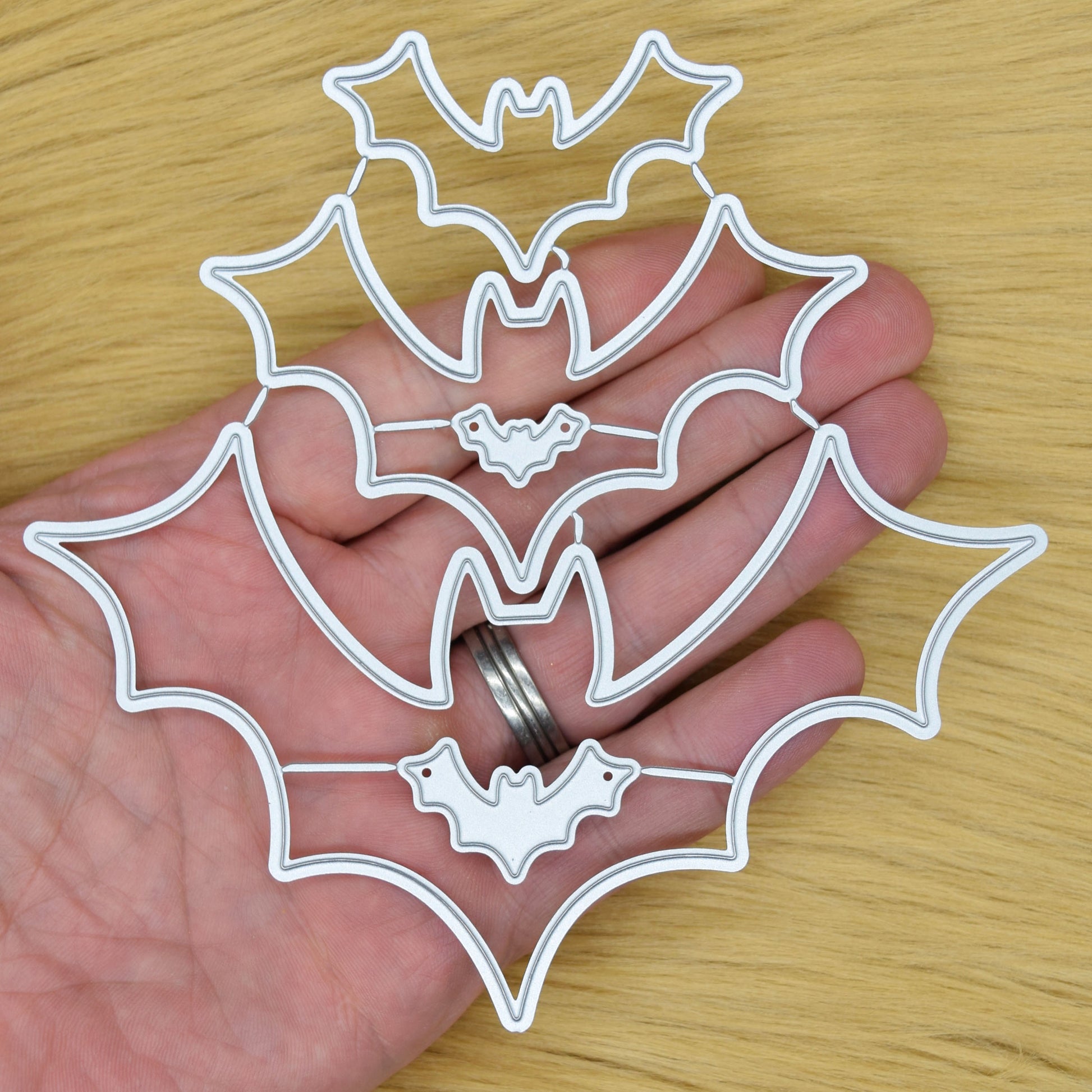 Bat nesting metal cutting dies held in hand showing size and scale