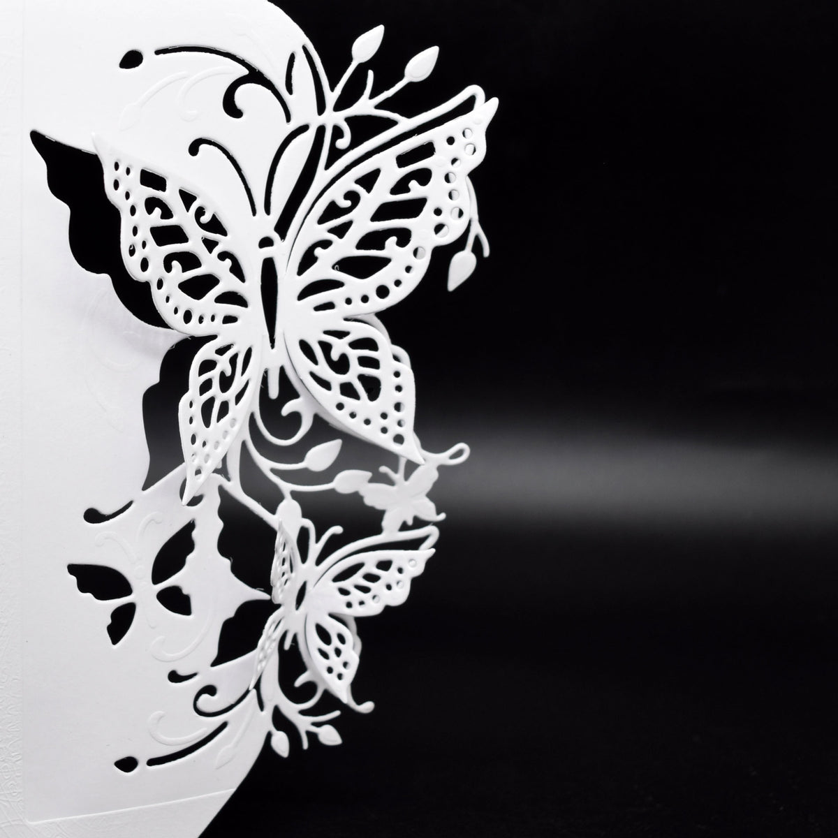 Finished white butterfly edge card showing the raised 3D effect created by the detailed butterfly metal cutting die.