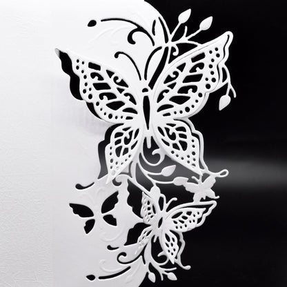 Detailed butterfly edge metal cutting die with finished white papercraft example showing butterflies, leaves and decorative flourishes.
