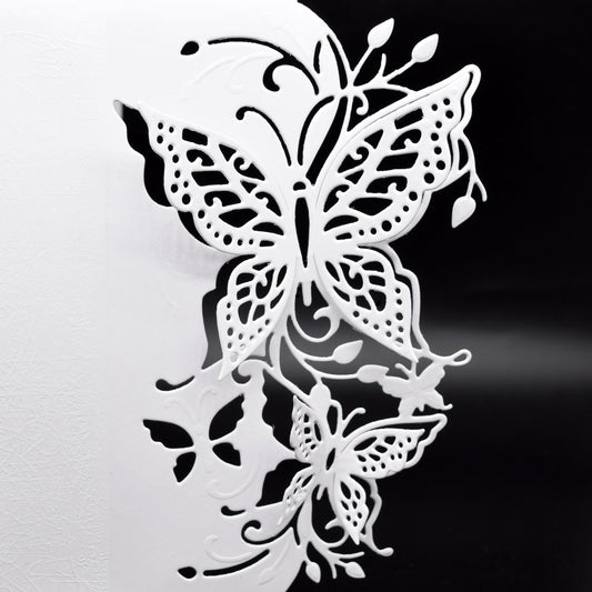 Detailed butterfly edge metal cutting die with finished white papercraft example showing butterflies, leaves and decorative flourishes.