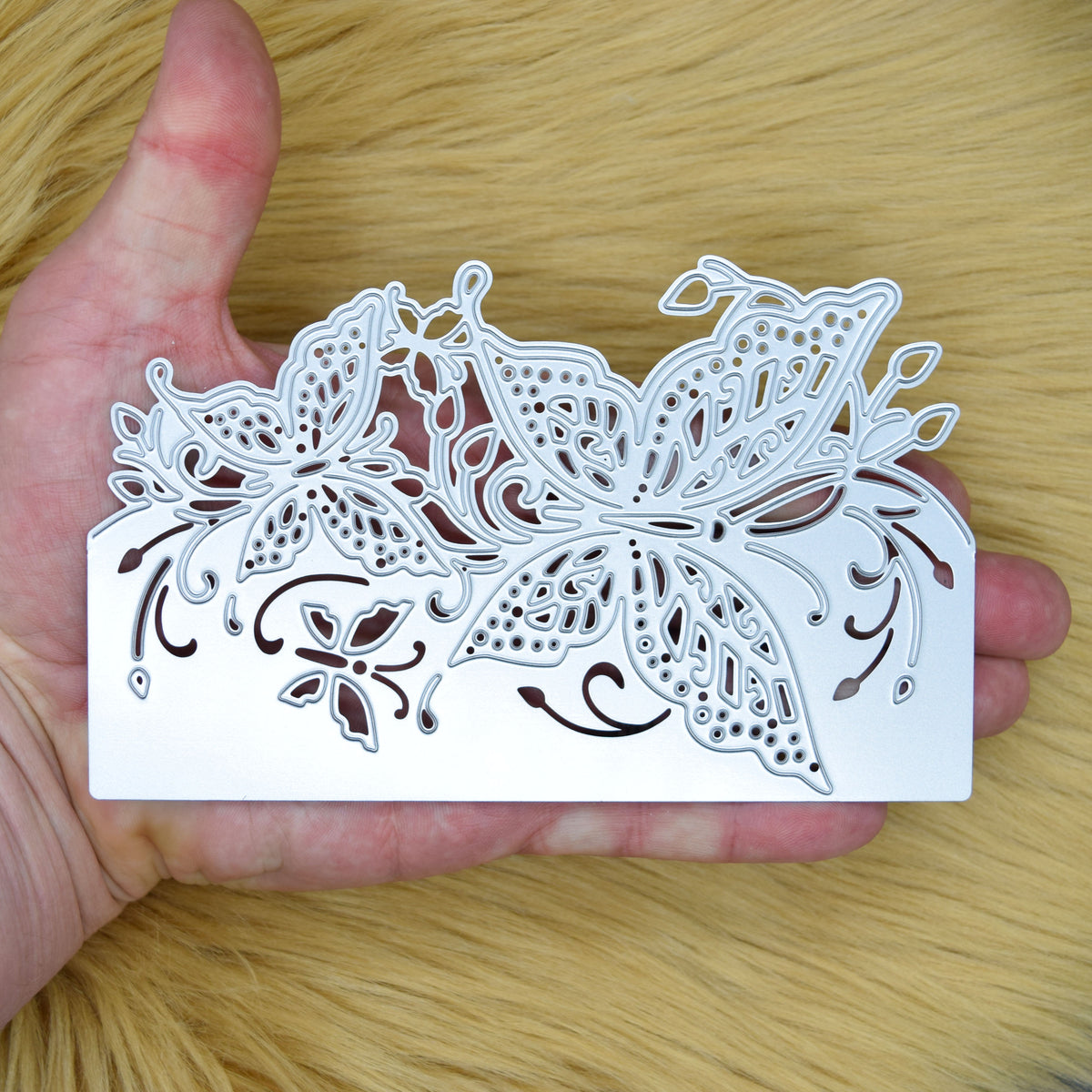 Large butterfly edge metal cutting die held in hand, showing the detailed butterflies, foliage and decorative cut-out design.