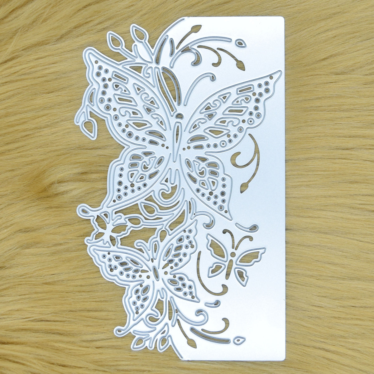 Detailed butterfly edge metal cutting die on faux fur background featuring two large butterflies, foliage and decorative cut-out flourishes.