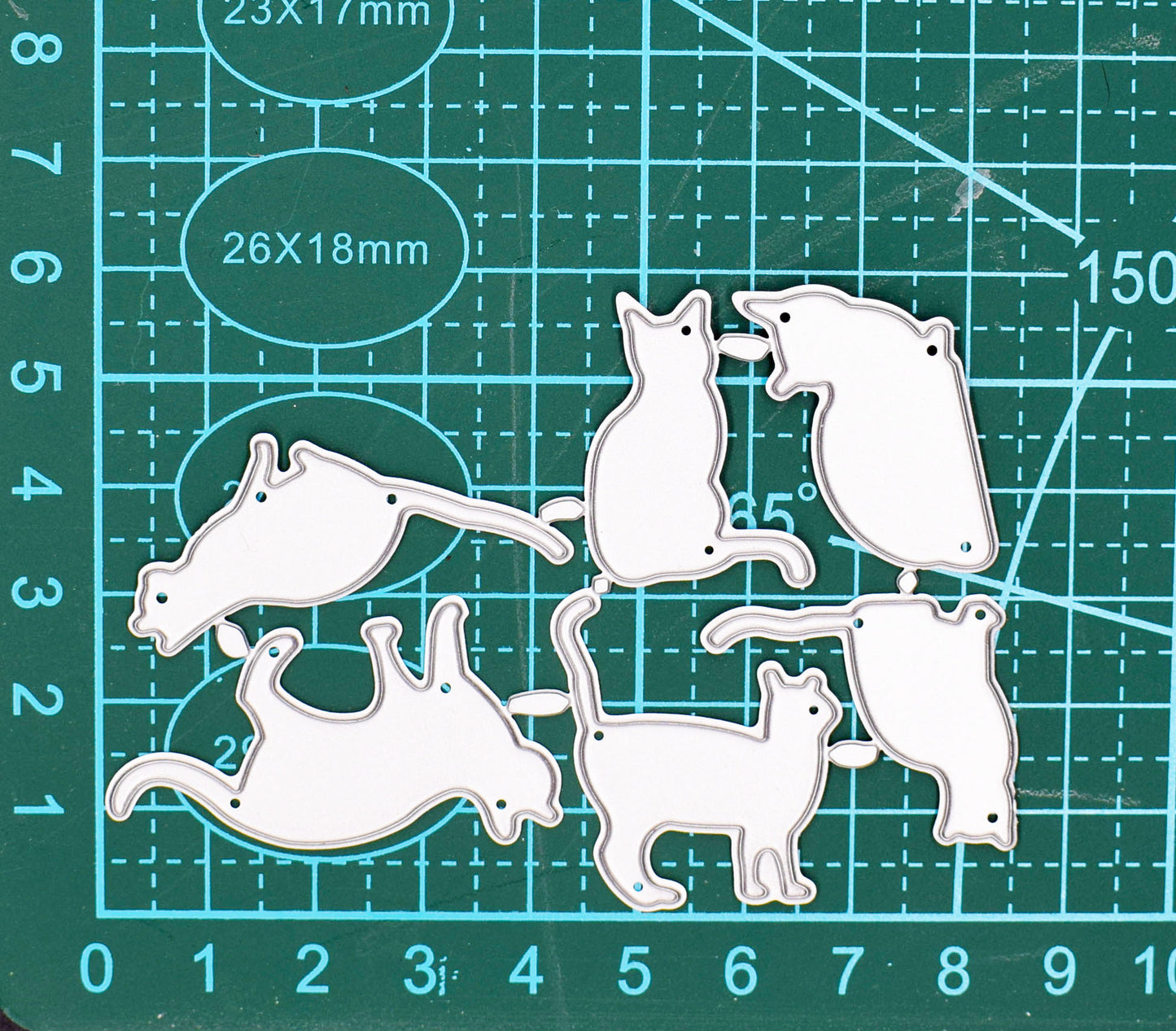 Six cat silhouette metal cutting dies displayed on a centimetre cutting mat for size reference