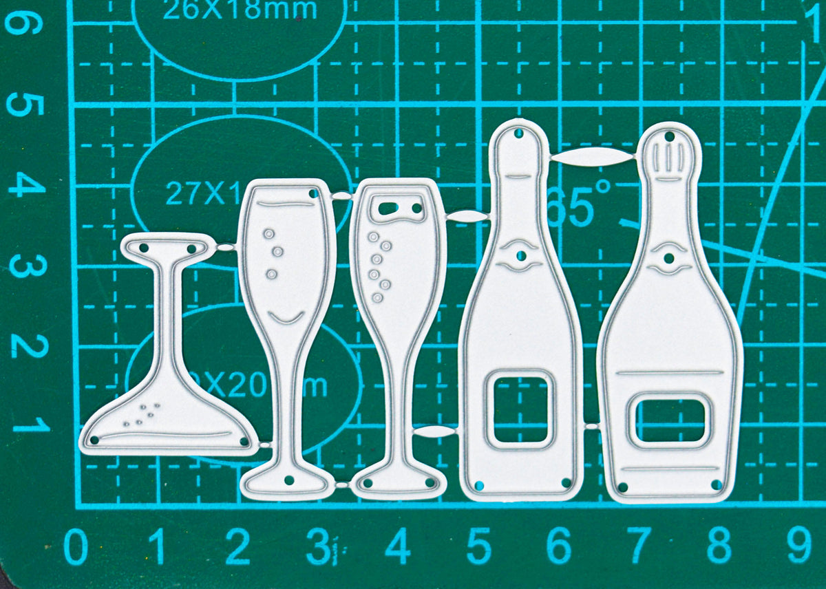Champagne bottle and glass metal cutting dies on a centimetre cutting mat, showing the overall set size for card making.