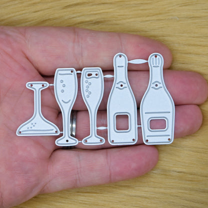 Champagne bottle and glass metal cutting die set held in a hand to show its size for wedding and anniversary card making.