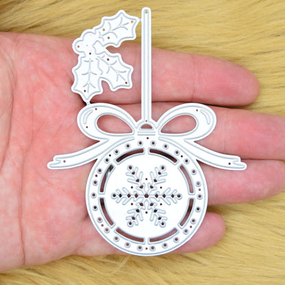 Christmas snowflake bauble metal cutting die held in hand to show the overall size and detailed holly, bow and ornament design.