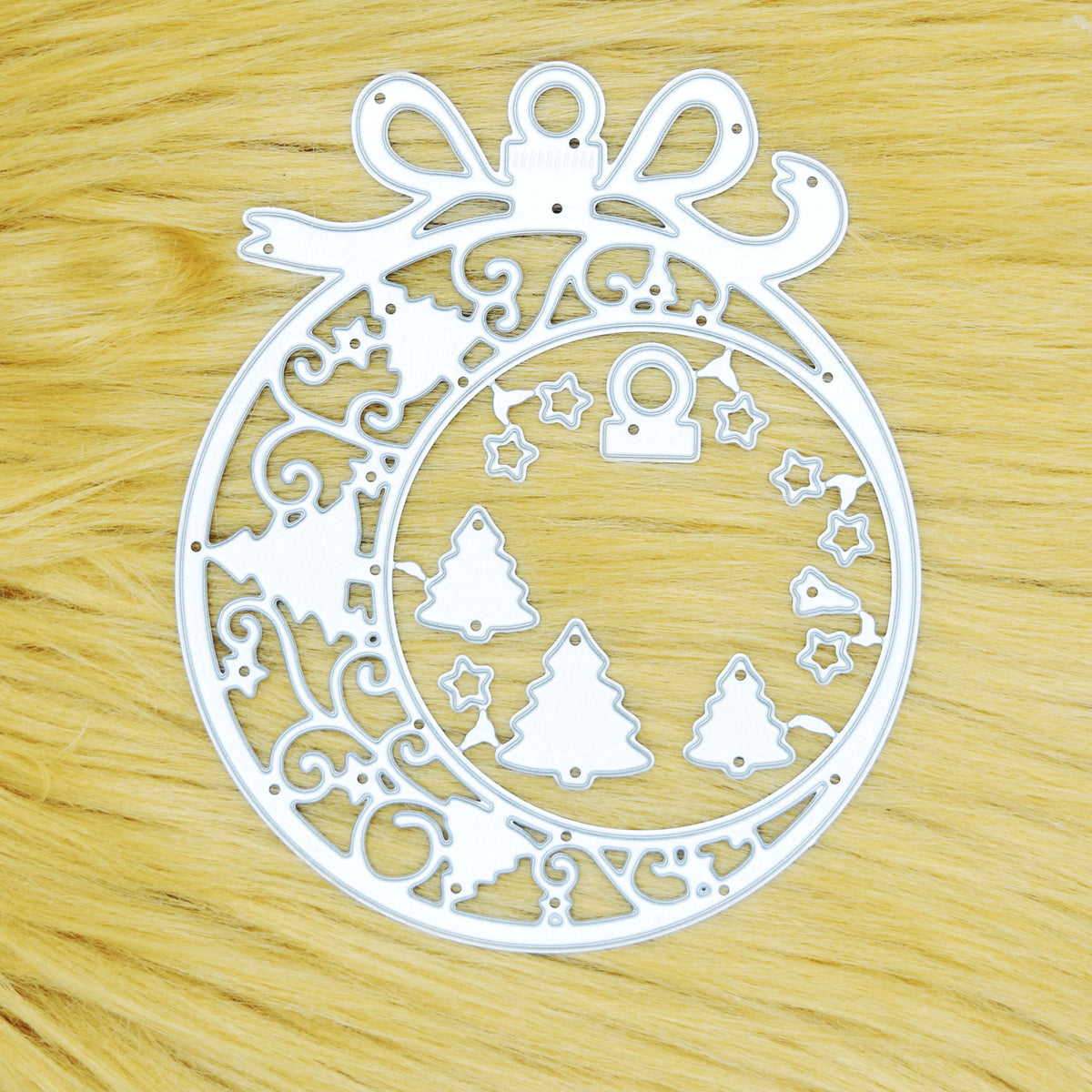 Christmas bauble frame metal cutting die set on a tan faux fur background, with tree and star embellishments for papercraft.