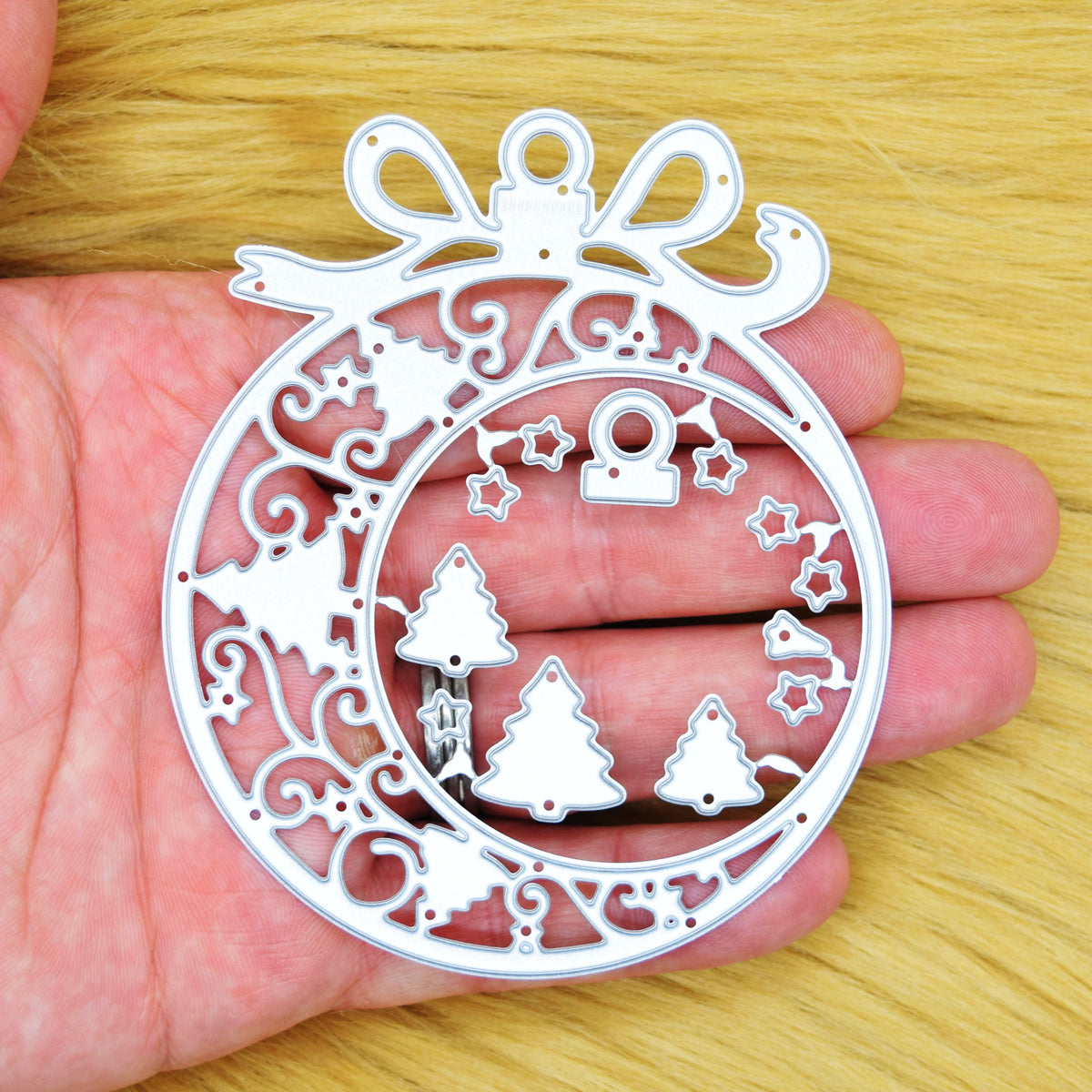 Christmas bauble frame metal cutting die set held in a hand to show its size for festive card making.