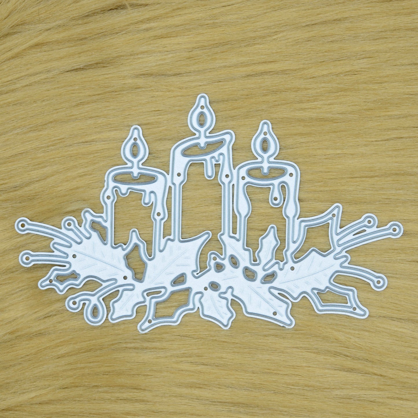 Christmas Candles & Holly metal cutting die displayed on a faux fur background for festive card making and papercraft projects.