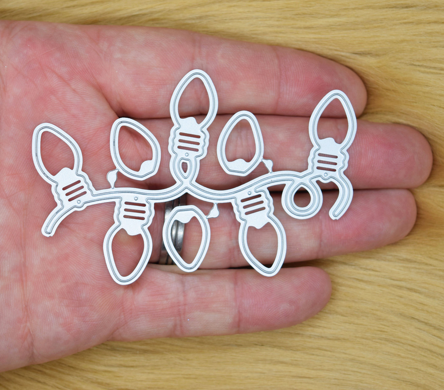 Christmas string light bulb metal cutting dies held in hand showing festive garland die set for card making