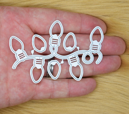 Christmas string light bulb metal cutting dies held in hand showing festive garland die set for card making