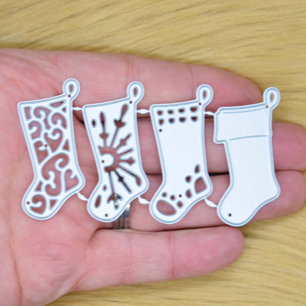 Four joined Christmas stocking metal cutting dies held in a hand to show their size.