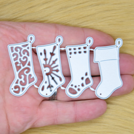 Four joined Christmas stocking metal cutting dies held in a hand to show their size.