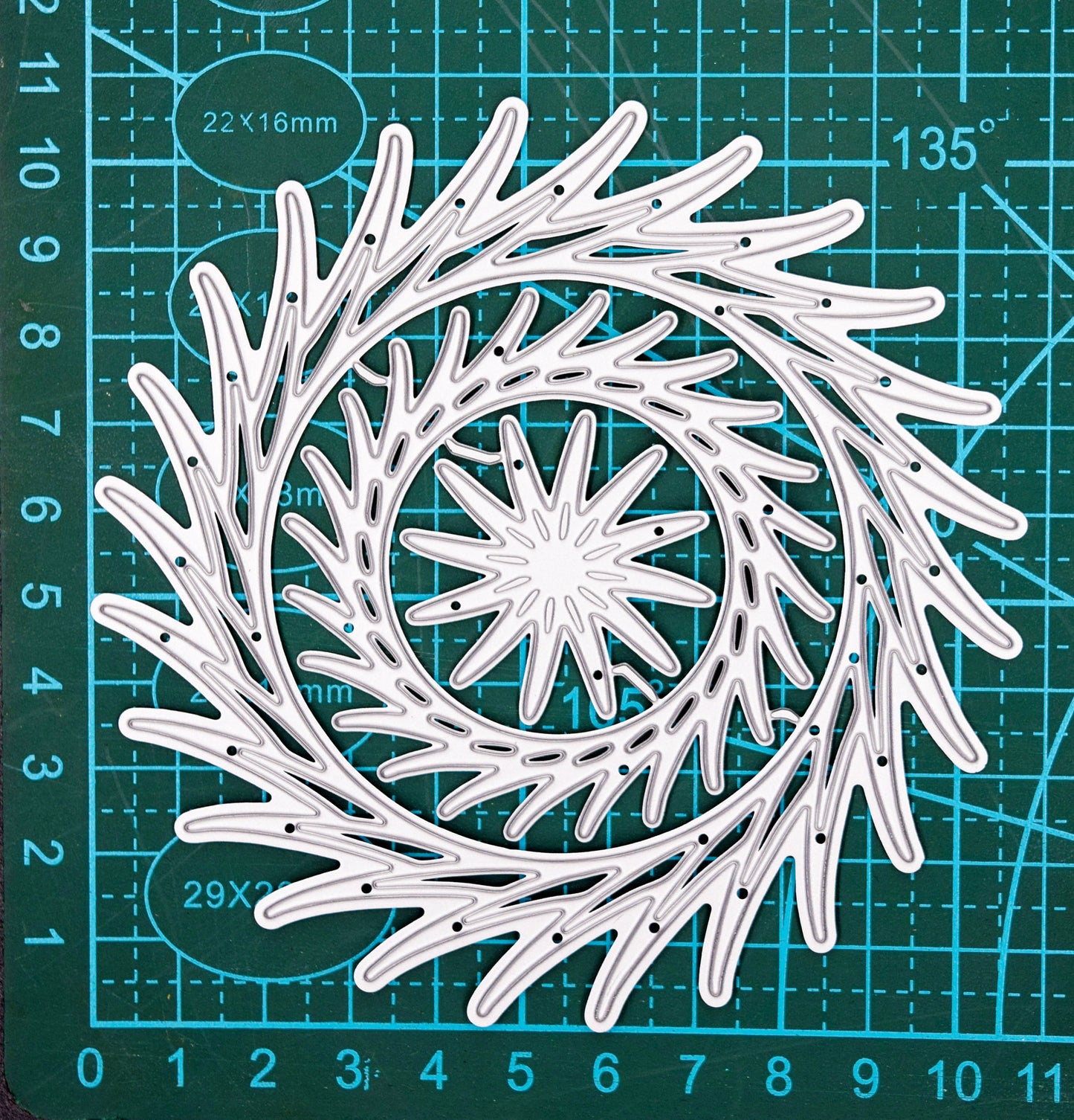 Decorative swirl circle dies on cutting mat for size reference