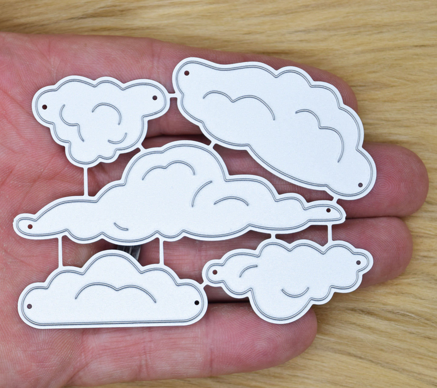 Cloud metal cutting dies set held in hand showing five different cloud shapes for card making