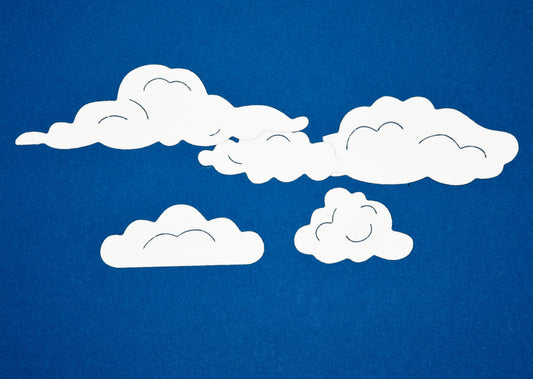 White cloud die cut shapes on blue background made using metal cutting dies