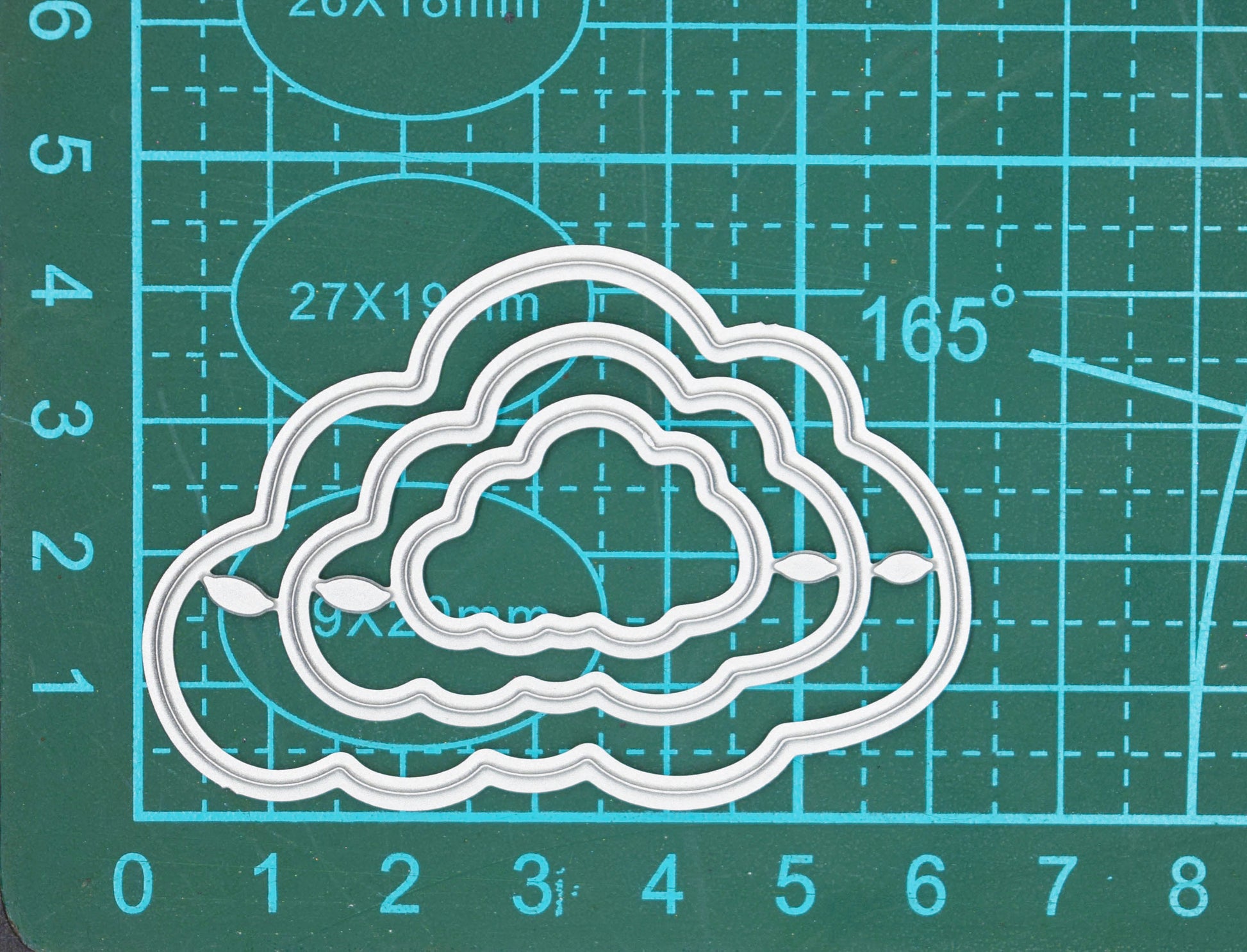 Cloud nesting dies photographed on cutting mat for sizing guidance
