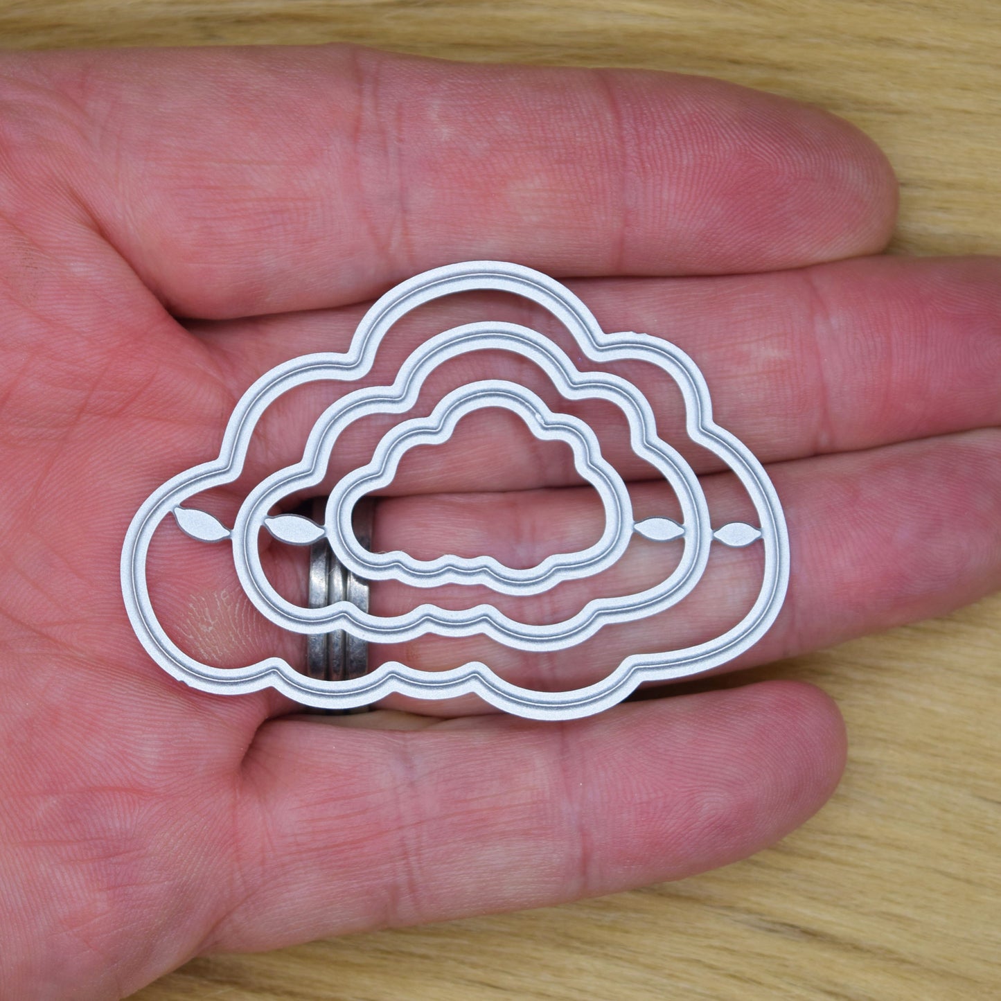 Set of 3 cloud nesting metal cutting dies shown in hand for scale reference