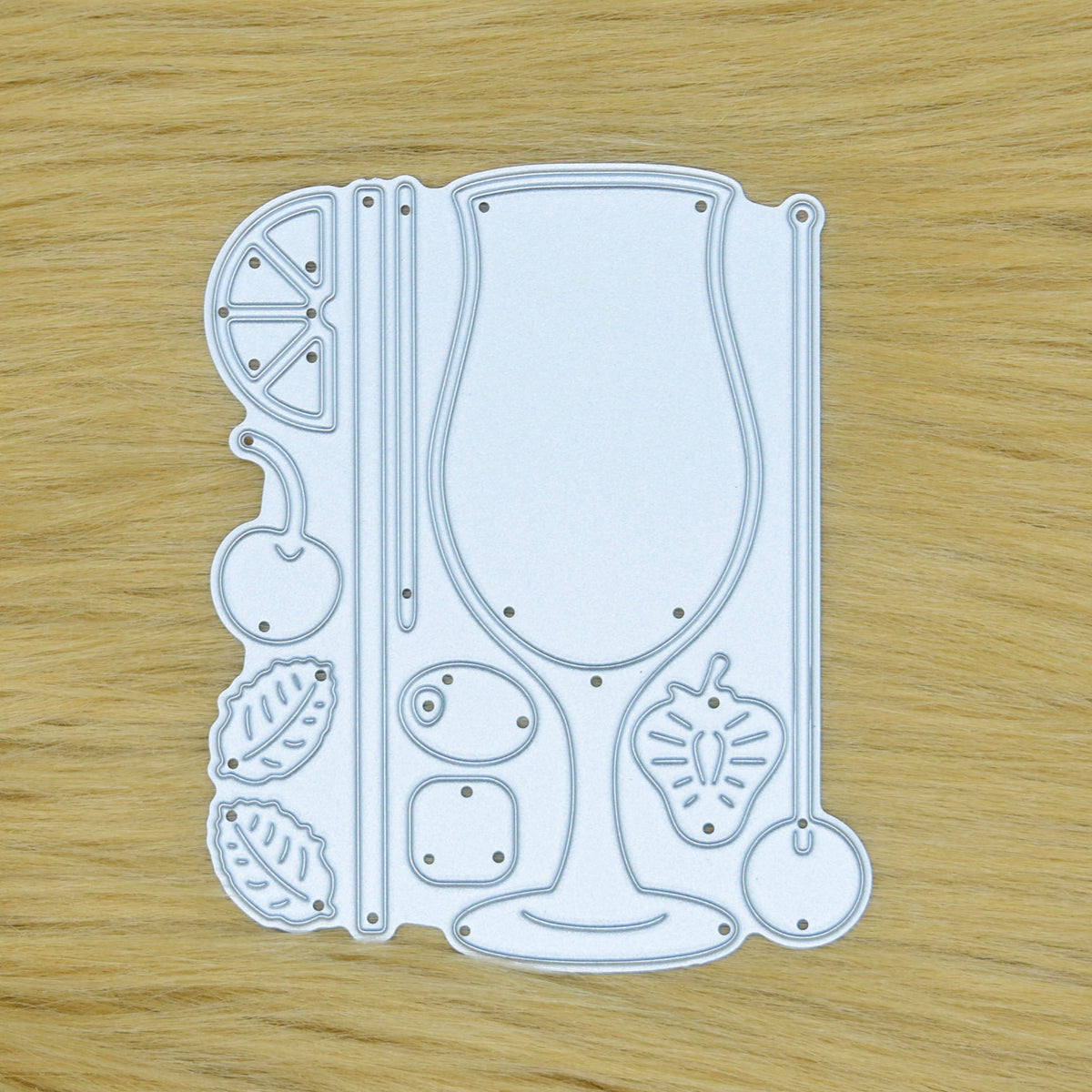 Cocktail glass and garnish metal cutting die set displayed on a faux fur background for card making and papercraft.