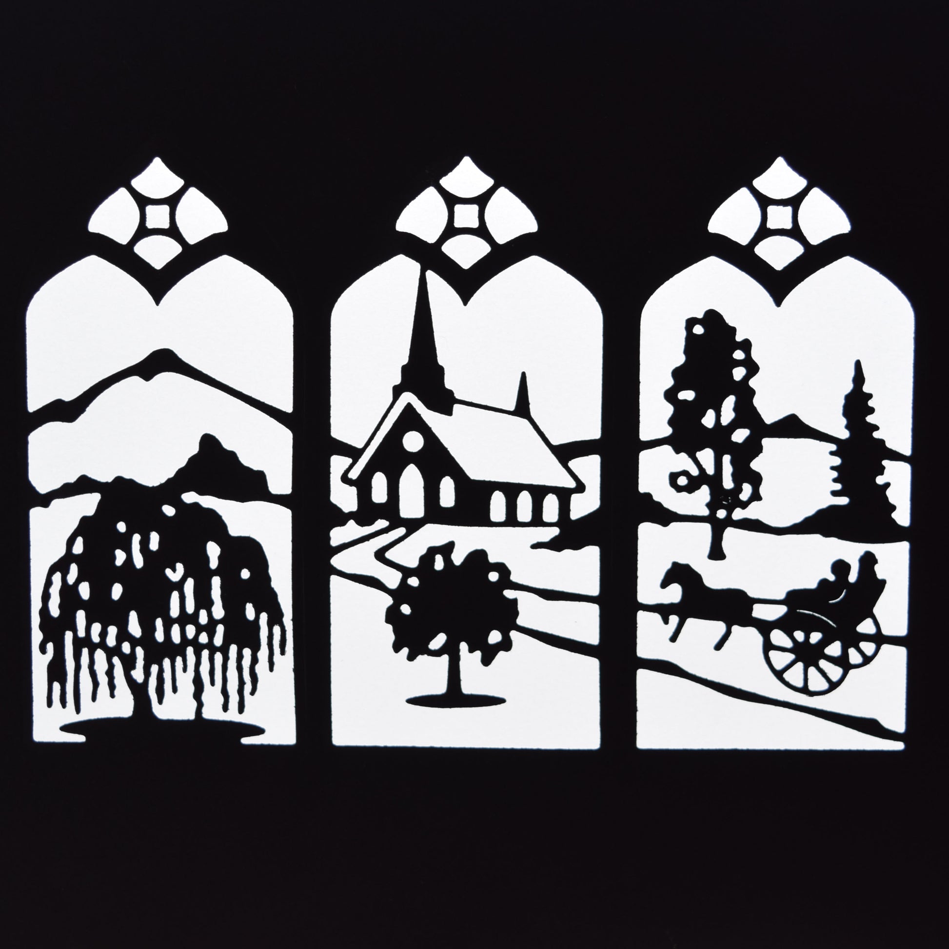 Finished black countryside window scene die cut showing a church, trees, mountains, horse and cart within three decorative arched panels.