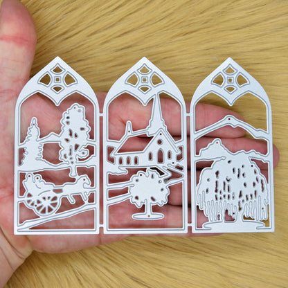 Three-panel countryside window scene metal cutting die shown in hand to demonstrate its size and detailed landscape design.