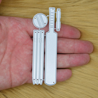 Cricket metal cutting die set held in hand to show the size of the bat, stumps, ball and bails dies