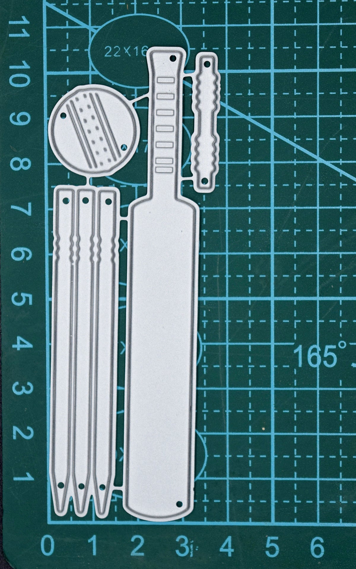 Cricket metal cutting die set displayed on a centimetre cutting mat showing the bat, stumps, ball and bails design