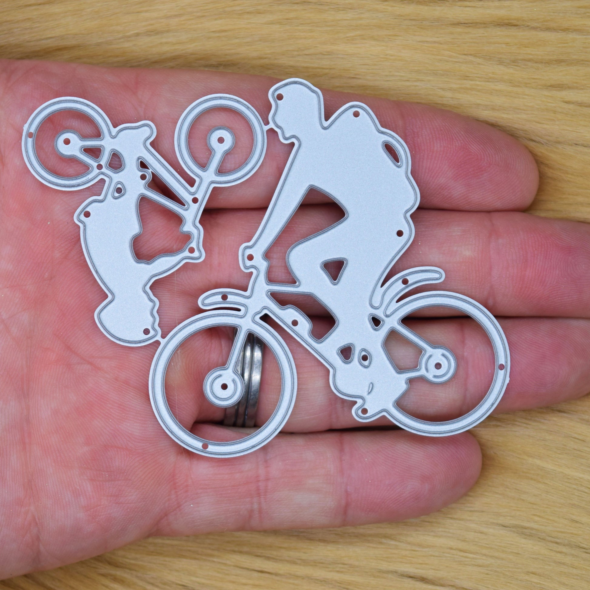 Man and child riding bicycles metal cutting die shown in hand for size reference with family cycling silhouette design for card making