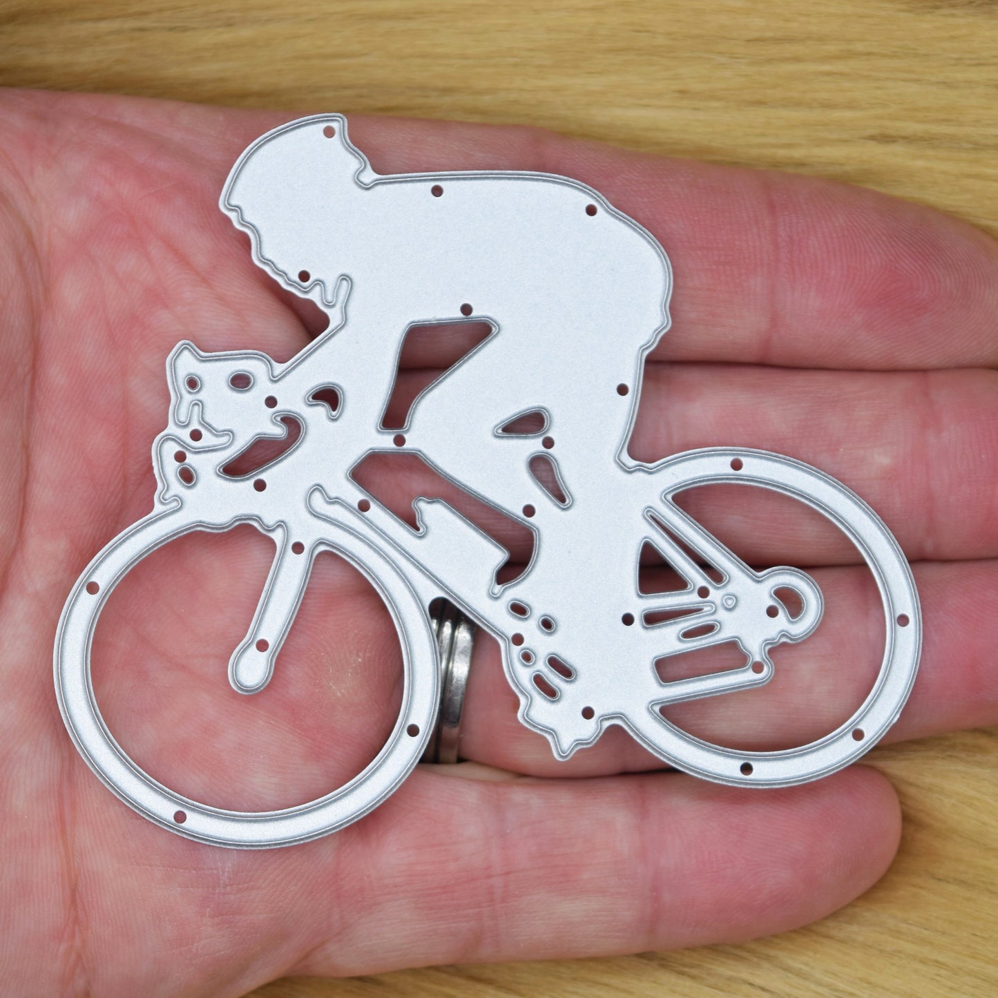 Cyclist metal cutting die held in hand for size showing detailed racing bicycle design
