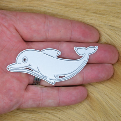 Dolphin metal cutting die held in hand showing size and sea life design for card making