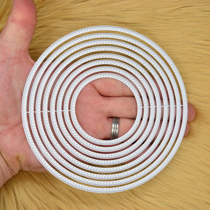 Large double stitch circle nesting metal cutting dies held in hand to show the graduated sizes and overall scale.