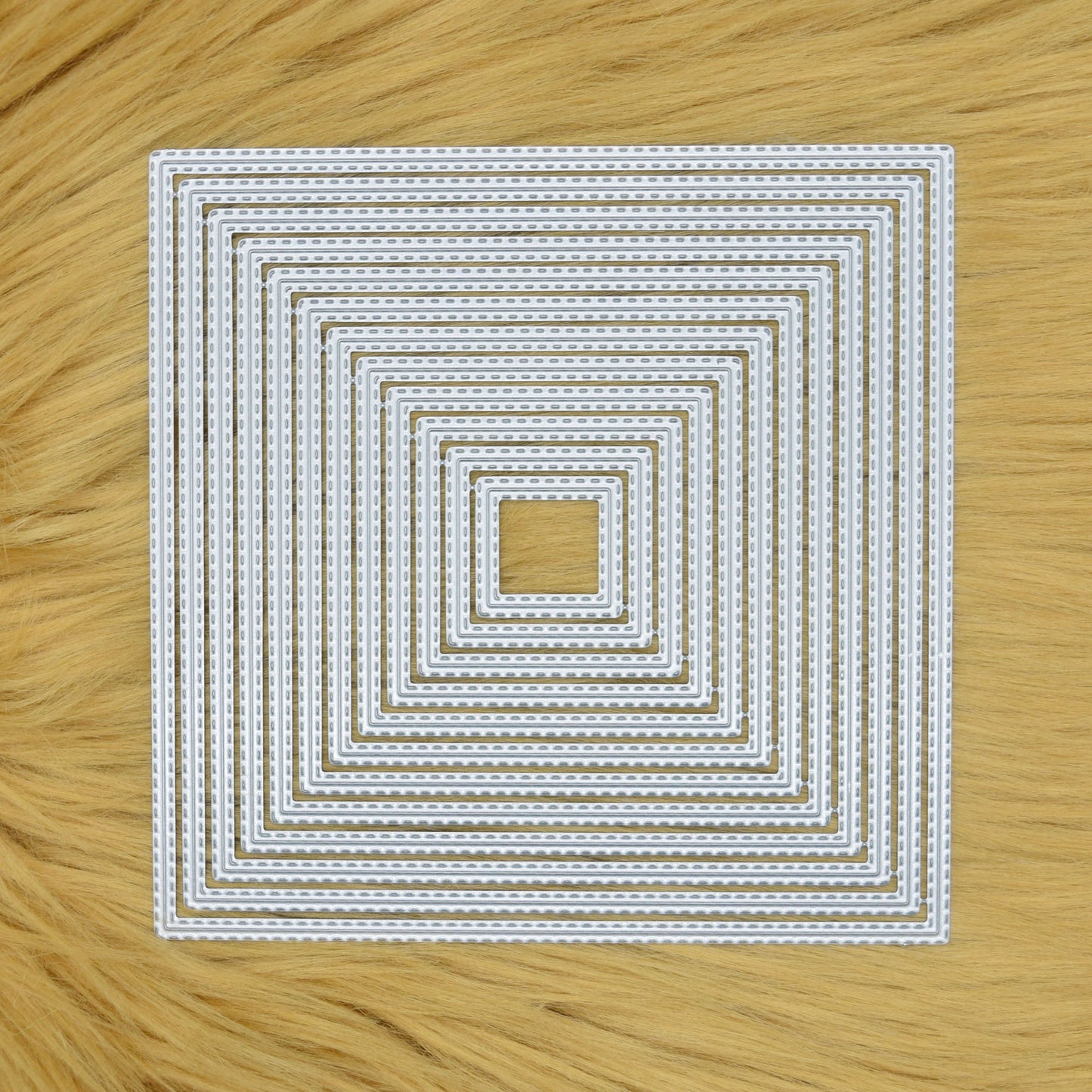 Set of 12 double stitched square nesting metal cutting dies displayed on a faux fur background.