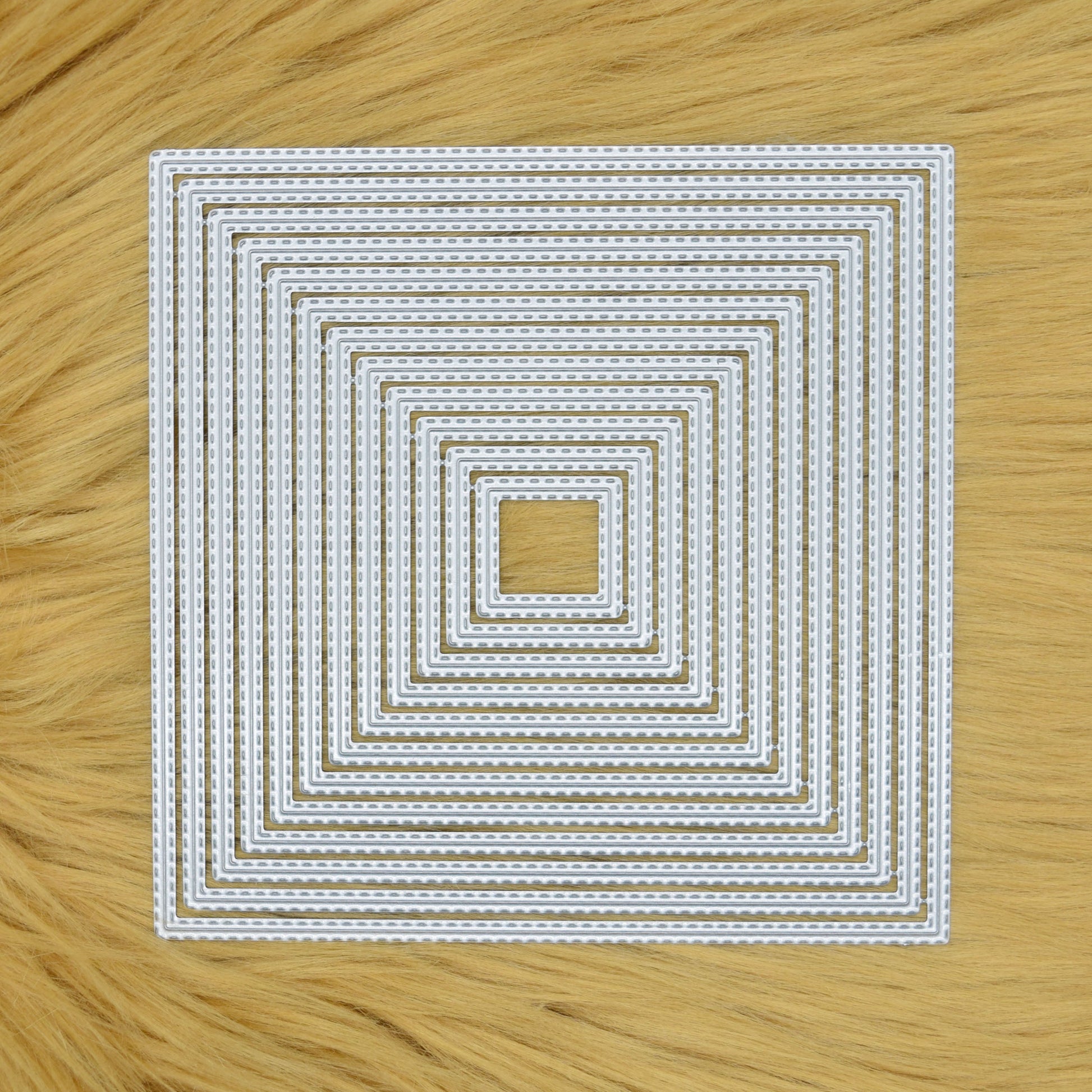 Set of 12 double stitched square nesting metal cutting dies displayed on a faux fur background.