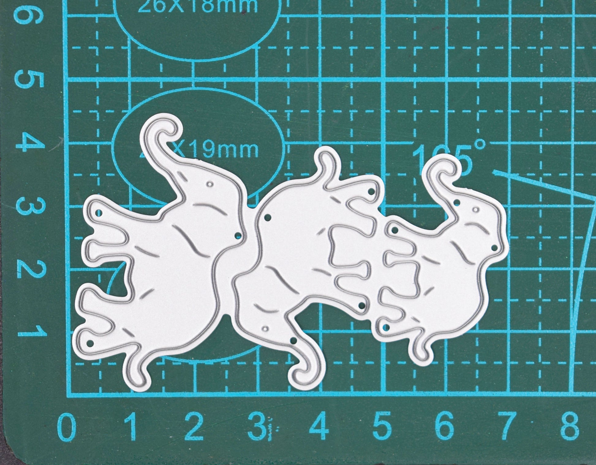 Three elephant metal cutting dies displayed on cutting mat showing approximate size for card making and scrapbook crafts