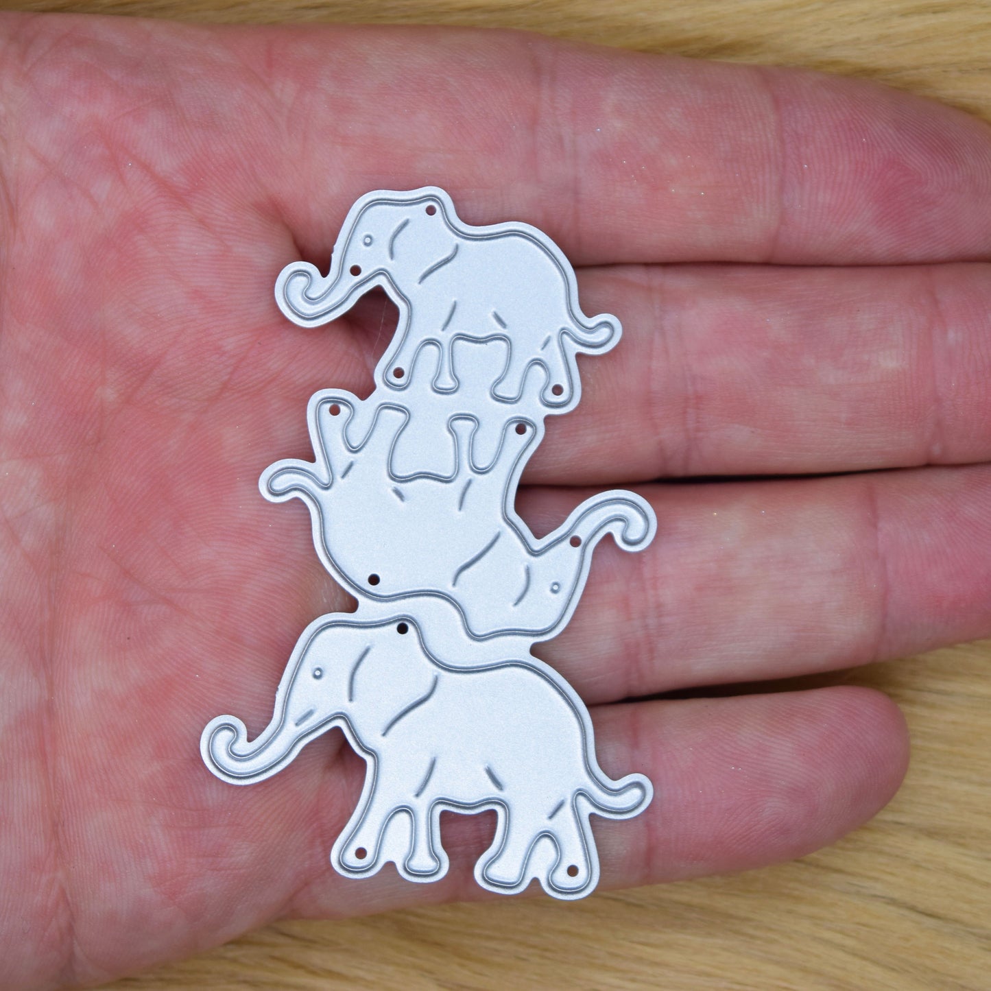 Elephant family metal cutting dies shown in hand for size reference suitable for handmade cards and papercraft projects