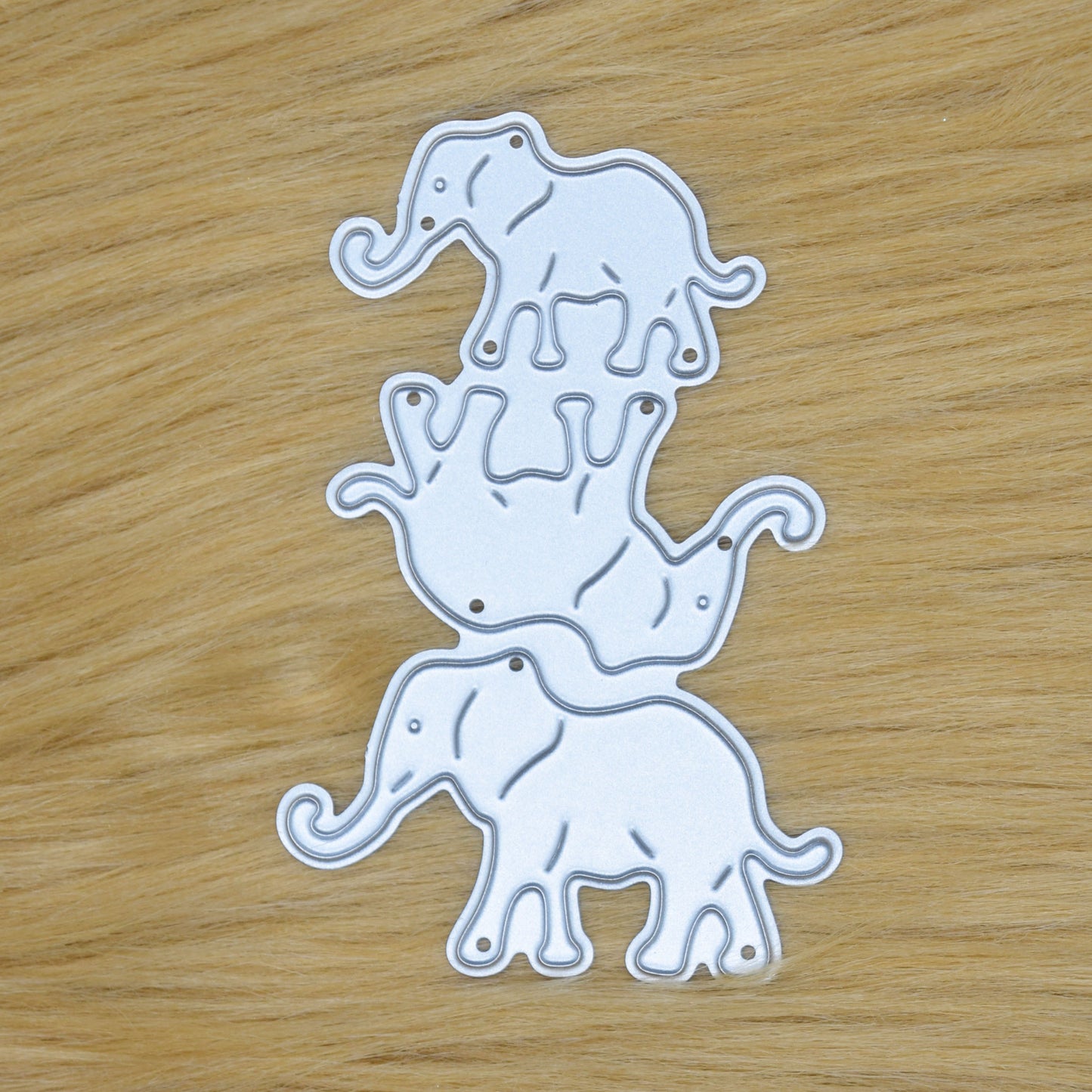 Elephant family metal cutting die set with three separate elephant designs shown on faux fur background for card making crafts
