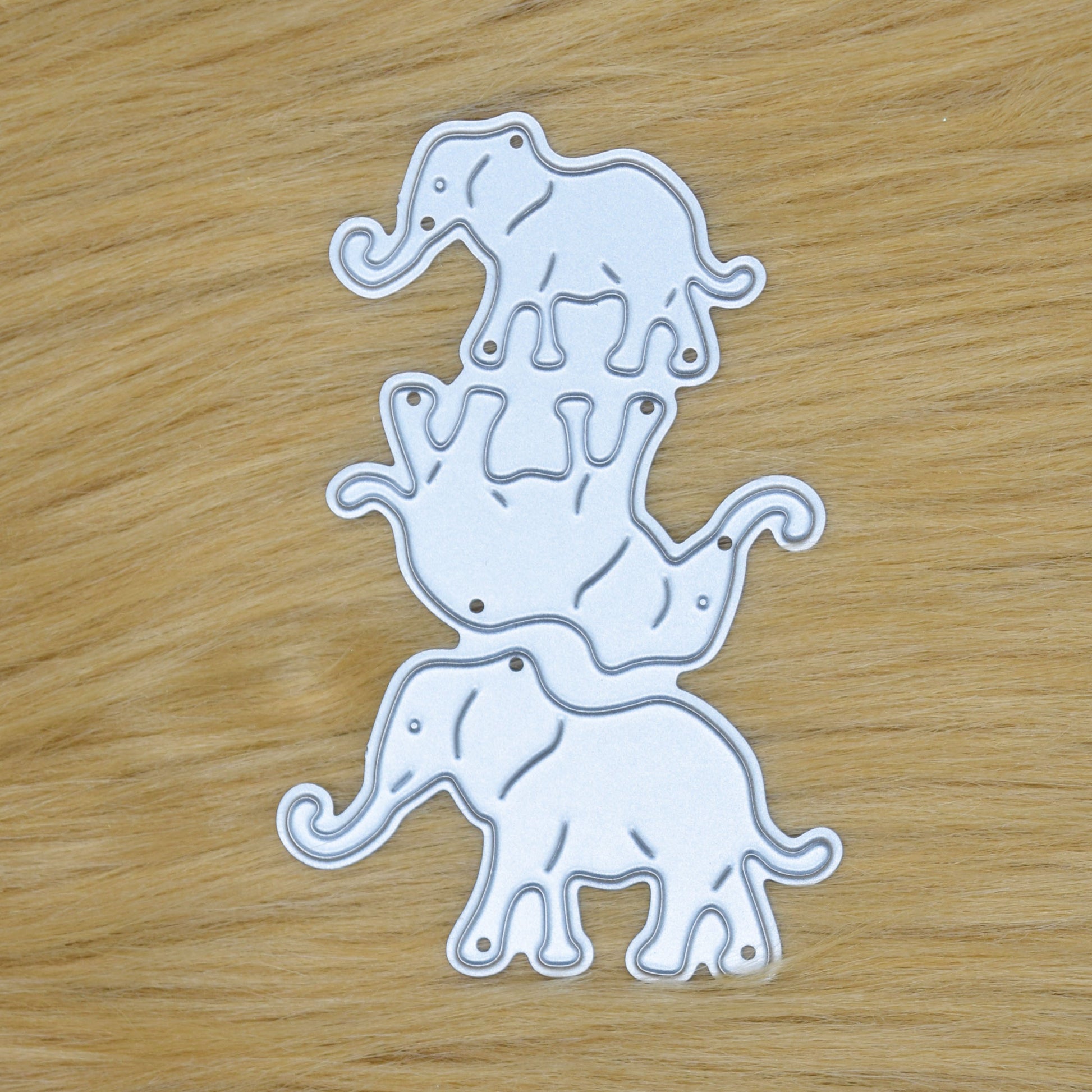 Elephant family metal cutting die set with three separate elephant designs shown on faux fur background for card making crafts