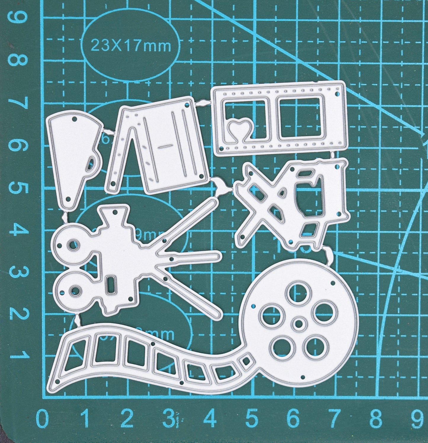 Movie and film themed metal cutting dies displayed on cutting mat showing cinema camera reel and director chair craft designs
